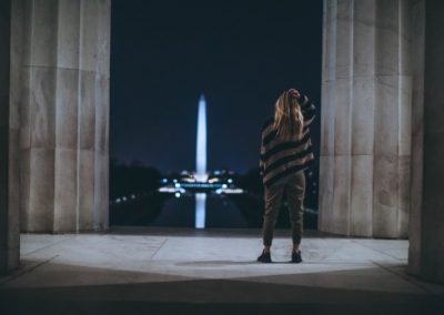 Student looking out at the Washington Monument lit up at night