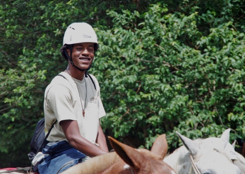 Student smiling at the camera while riding a horse
