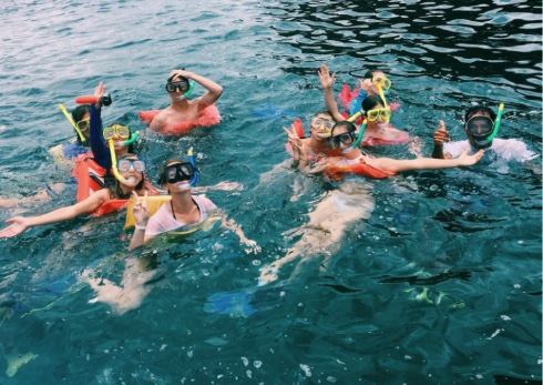 A group of students looking at the camera while in the water with snorkel gear
