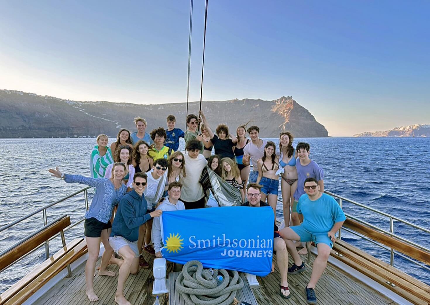 Students holding Smithsonian Journeys flag while on a boat