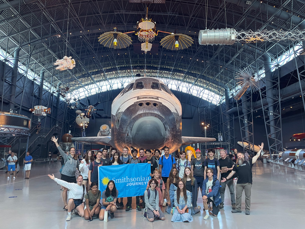 Students smiling in front of space shuttle