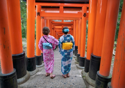 two students walking under red gates in japan